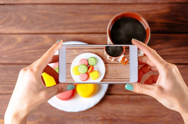 Kobieta bierze fotografię macarons deserowi.