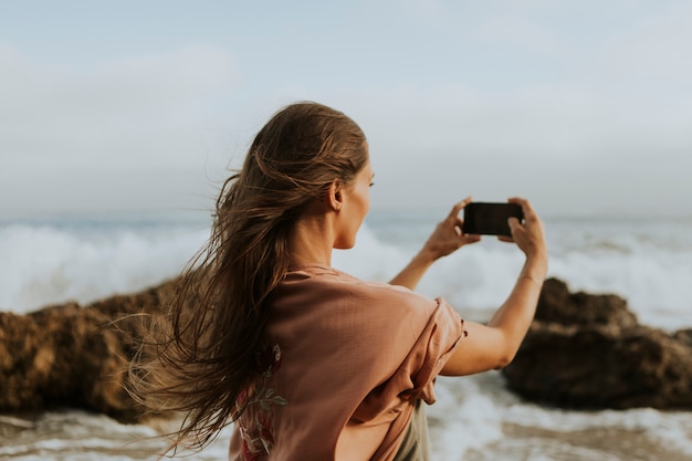 Kobieta bierze fotografie z jej telefonem na plaży