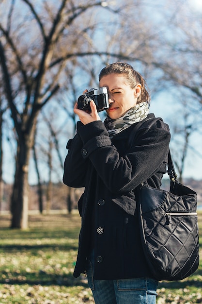 Zdjęcie kobieta bierze fotografię z starym analogowym aparatem