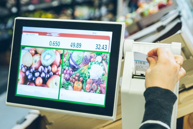 Kobieta bierze naklejkę z ceną po zważeniu produktów