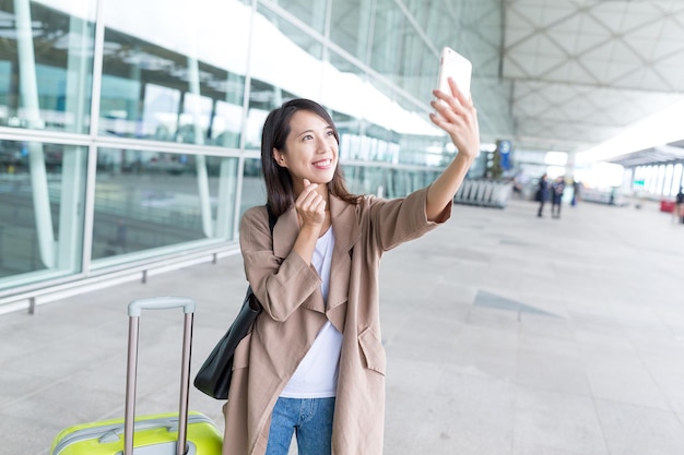 Kobieta biorąc selfie przez telefon komórkowy na lotnisku