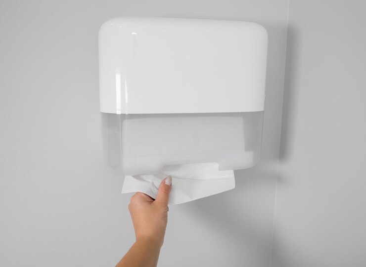 Kobieta biorąca nowy świeży papierowy ręcznik z dozownika w łazience