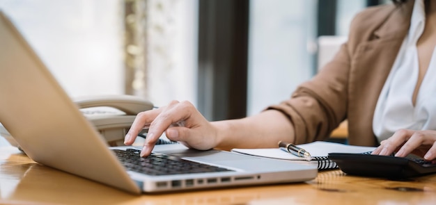 Kobieta biznesmen pracuje na biurku za pomocą kalkulatora do obliczania koncepcji rachunkowości finansów