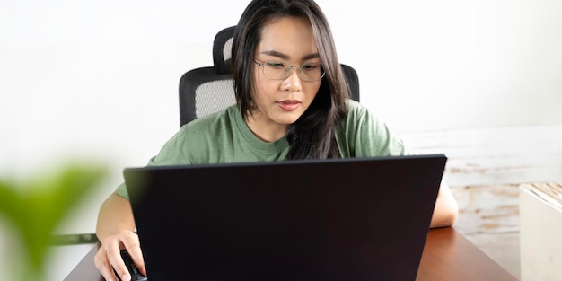 Kobieta biznesowa pracująca w biurze przy swoim biurku z uśmiechem na laptopie i dialogem biznesowym za pośrednictwem łącza wideo