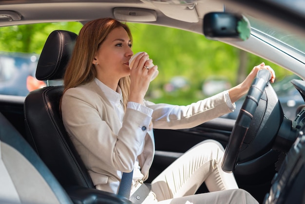 Kobieta biznesu lub kierowca prowadzący samochód i pijący kawę na wynos
