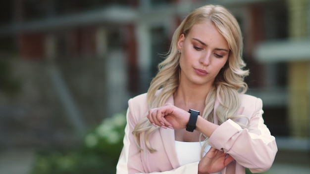 Zdjęcie kobieta biznesu przeznaczone do walki radioelektronicznej spojrzenie na inteligentny zegarek kobieta spojrzenie na zegarek na zewnątrz