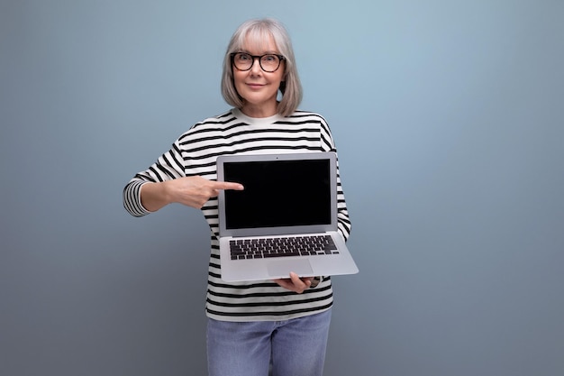 Kobieta biznesu w średnim wieku demonstruje ekran laptopa z makietą reklamową na jasnym