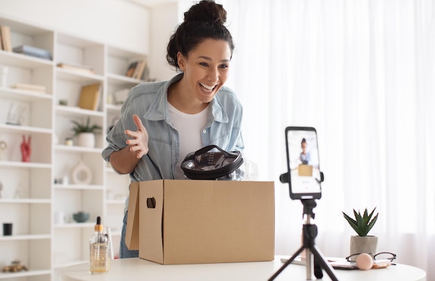 Kobieta blogerka do makijażu robi wideo na pudełku rozpakowywania telefonu w pomieszczeniu