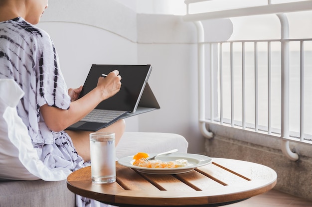 Kobieta Budząca Się Na Laptopie Typu Tablet Ze Szklanką Wody I świeżymi Owocami Na Stole