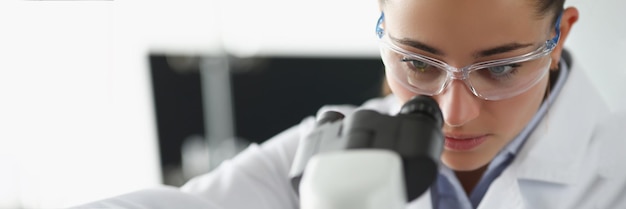 Zdjęcie kobieta chemik bada próbkę pod mikroskopem w laboratorium