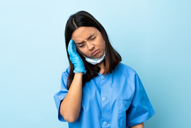 Kobieta chirurg na niebieską ścianą z bólem głowy