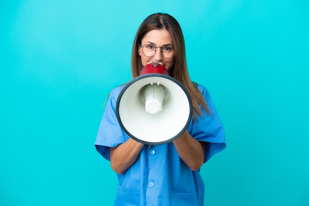 Kobieta chirurg w średnim wieku na niebieskim tle krzycząca przez megafon