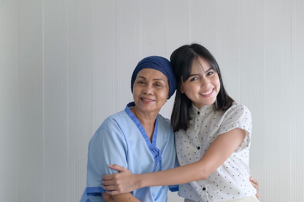 Kobieta chora na raka nosząca chustę na głowie i wspierająca ją córka w szpitalu