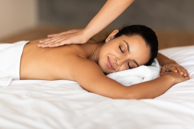 Kobieta cieszy się masażem w spa, podczas gdy terapeut masuje jej plecy.