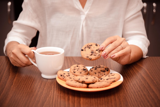 Zdjęcie kobieta cieszy się przerwą w pracy z ciastkiem i herbatą proste przyjemności jedzenia