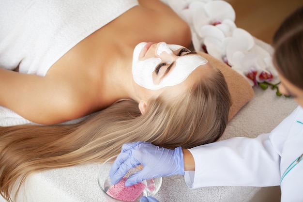 Kobieta coraz pielęgnacji twarzy przez kosmetyczki w salonie spa