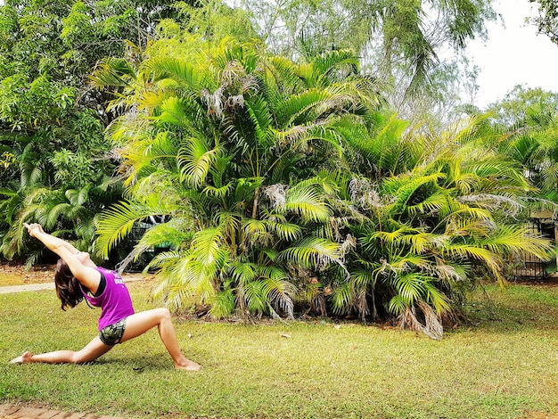 Kobieta ćwicząca jogę na trawiastym polu na podwórku