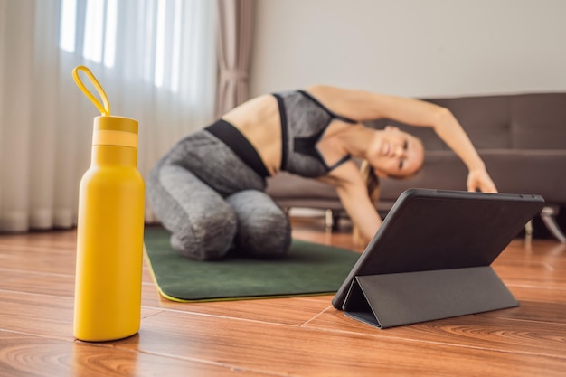 Kobieta ćwicząca na podłodze w domu i oglądająca filmy fitness na tabletie