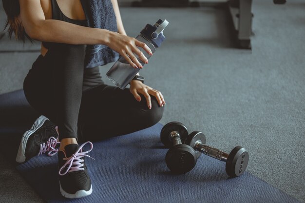 Zdjęcie kobieta ćwiczenia treningowe w siłowni fitness łamanie relaks po treningu sportowym z hantlami