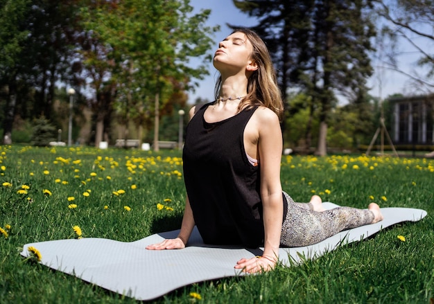 Kobieta ćwiczy jogę w asanie w parku harmonia i równowaga ciała używa maty