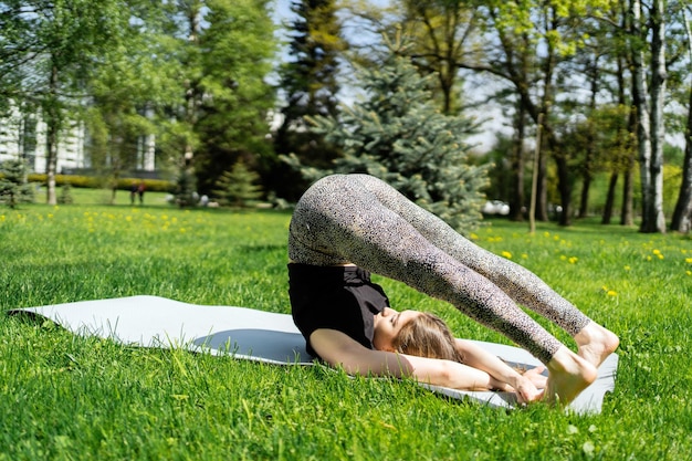 Kobieta ćwiczy jogę w asanie w parku harmonia i równowaga ciała używa maty