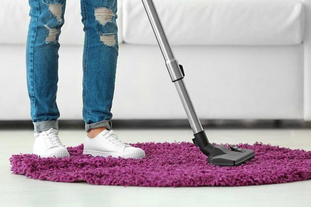 Kobieta czyści mały dywanik z próżnią w salonie
