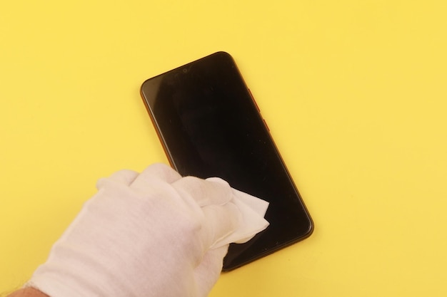 Kobieta czyści telefon komórkowy ściereczką antyseptyczną