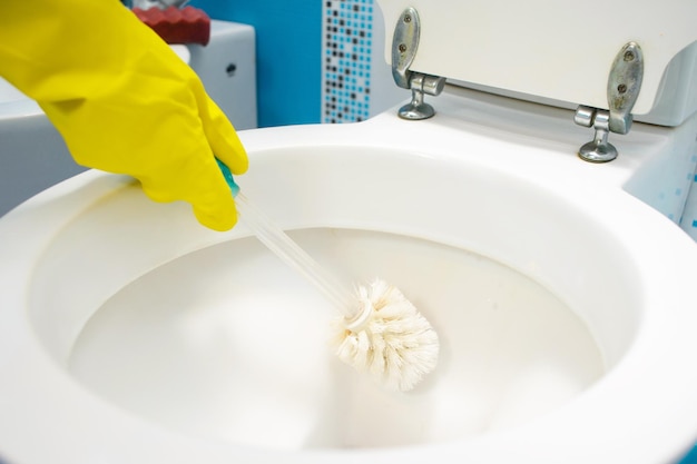 Kobieta czyści toaletę w łazience za pomocą szczotki do szorowania