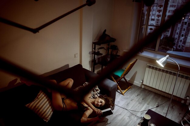 Zdjęcie kobieta czyta książkę leżąc w domu na kanapie