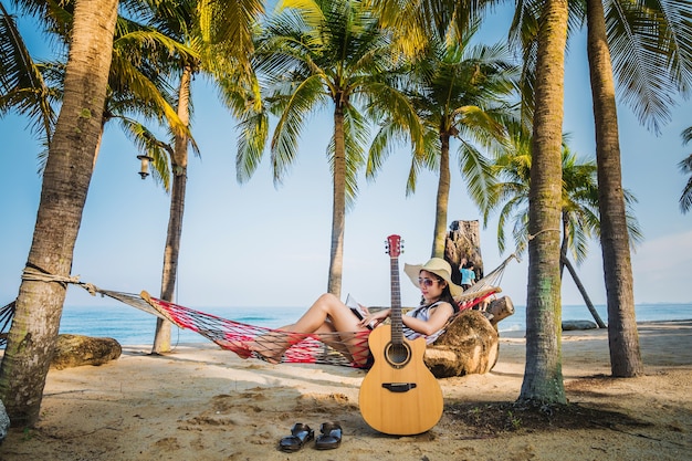 Kobieta czyta książkę na hamaku pod kokosowym drzewem podczas wakacje.