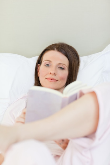 Kobieta czyta książkę na jej łóżku