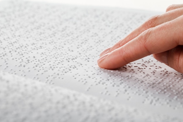 Zdjęcie kobieta czyta książkę napisaną alfabetem braille'a.