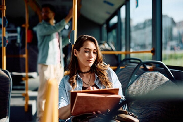 kobieta czytająca książkę w autobusie z mężczyzną na tle