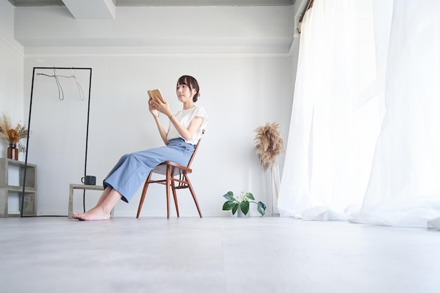 Kobieta czytająca książkę w prostym pokoju