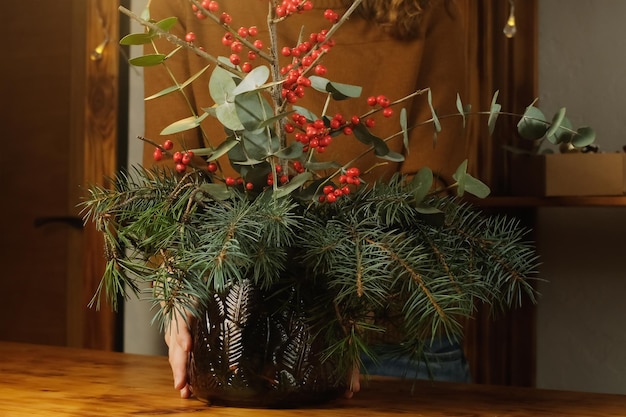 Kobieta dekorująca wnętrze domu świąteczną kompozycją kwiatową w wazonie
