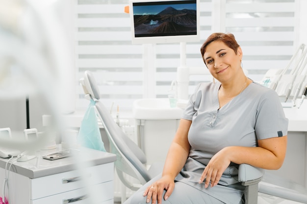 Kobieta dentysta przy jej biurowy ono uśmiecha się