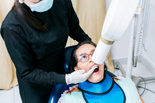 Kobieta dentysta robi prześwietlenie dentystyczne Kobieta dentystka robi prześwietlenie pacjentowi Kobieta dentysta robi prześwietlenie dentystyczne RTG stomatologiczne