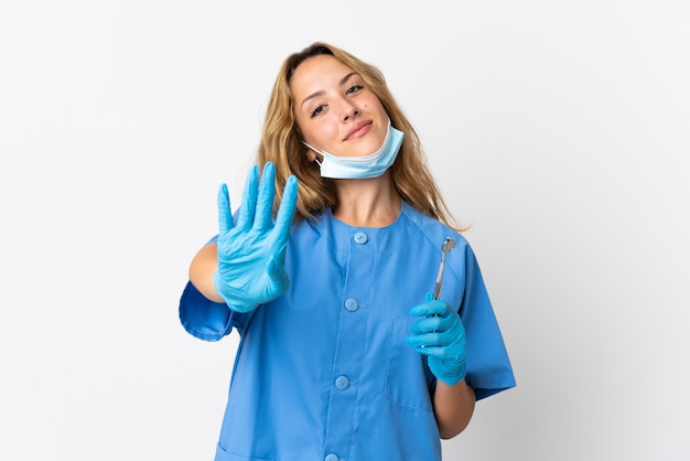 Kobieta dentysta trzymając narzędzia na białym tle na białej ścianie szczęśliwy i licząc cztery palcami
