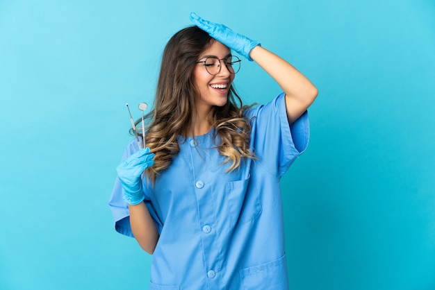 Kobieta dentysta trzymając narzędzia na białym tle na niebieskim tle coś sobie uświadomił i zamierza rozwiązać