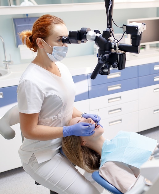 Kobieta dentysta z narzędziami dentystycznymi - mikroskop, lustro i sonda do leczenia zębów pacjenta w gabinecie stomatologicznym, Medycyna, stomatologia i opieka zdrowotna, Sprzęt dentystyczny