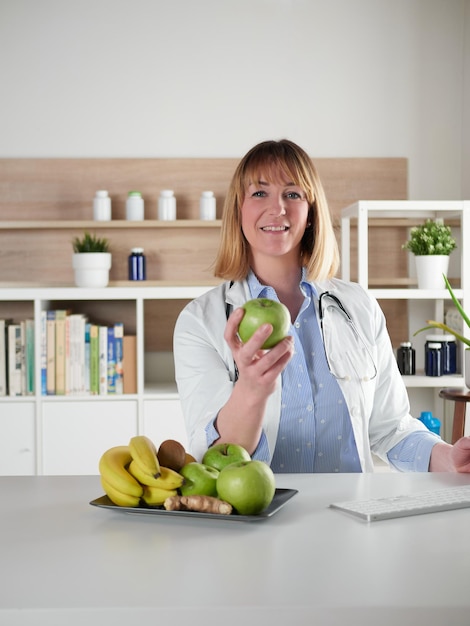 Kobieta dietetyk trzyma zielone jabłko w studiu biurowym