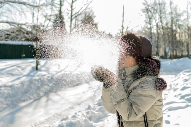 Zdjęcie kobieta dmuchająca śnieg, stojąc na polu