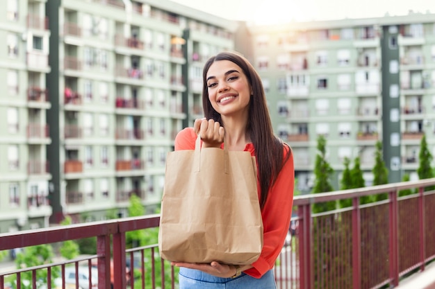 Kobieta dostarcza jedzenie w papierowej torbie. Dostawa jedzenia w domu.