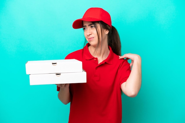Kobieta dostarczająca pizzę w mundurze roboczym, odbierająca pudełka po pizzy na białym tle na niebieskim tle, cierpiąca na ból w ramieniu za wysiłek