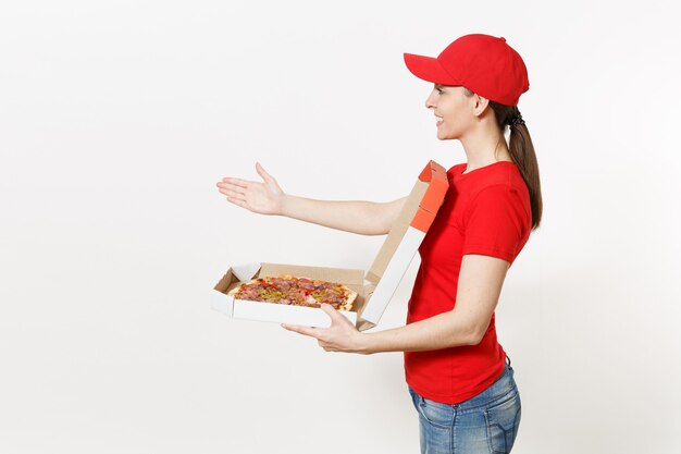Kobieta dostawy w czerwonym mundurze na białym tle. Ładna kobieta w czapce, koszulce, dżinsach pracujących jako kurier lub sprzedawca, trzymający włoską pizzę w kartonowym pudełku. Skopiuj miejsce na reklamę.