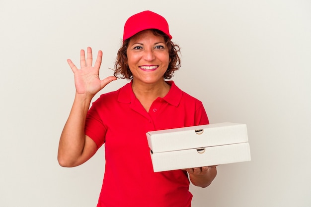 Kobieta dostawy w średnim wieku biorąc pizze na białym tle uśmiechnięty wesoły pokazując numer pięć palcami.