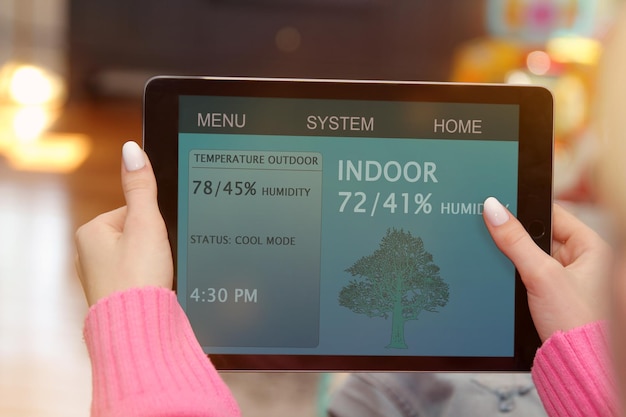 Zdjęcie kobieta dostosowuje temperaturę za pomocą tabletu z aplikacją inteligentnego domu w nowoczesnym salonie