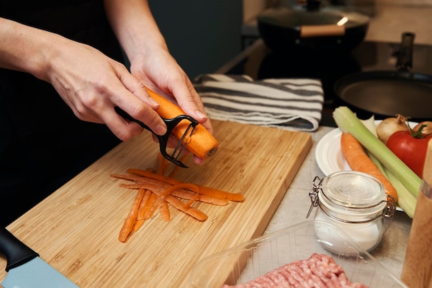 Kobieta drapie marchewkę w kuchni, z bliska