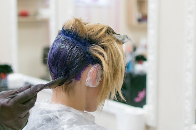 Kobieta farbowała włosy na niebiesko u fryzjera Kreatywne strzyżenie i zmiana wizerunku kobiety Stylista fryzjerski wykonujący swoją pracę w salonie