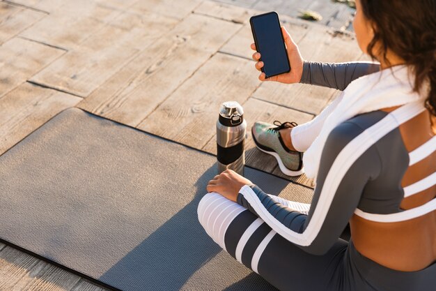 Kobieta fitness na zewnątrz za pomocą telefonu komórkowego